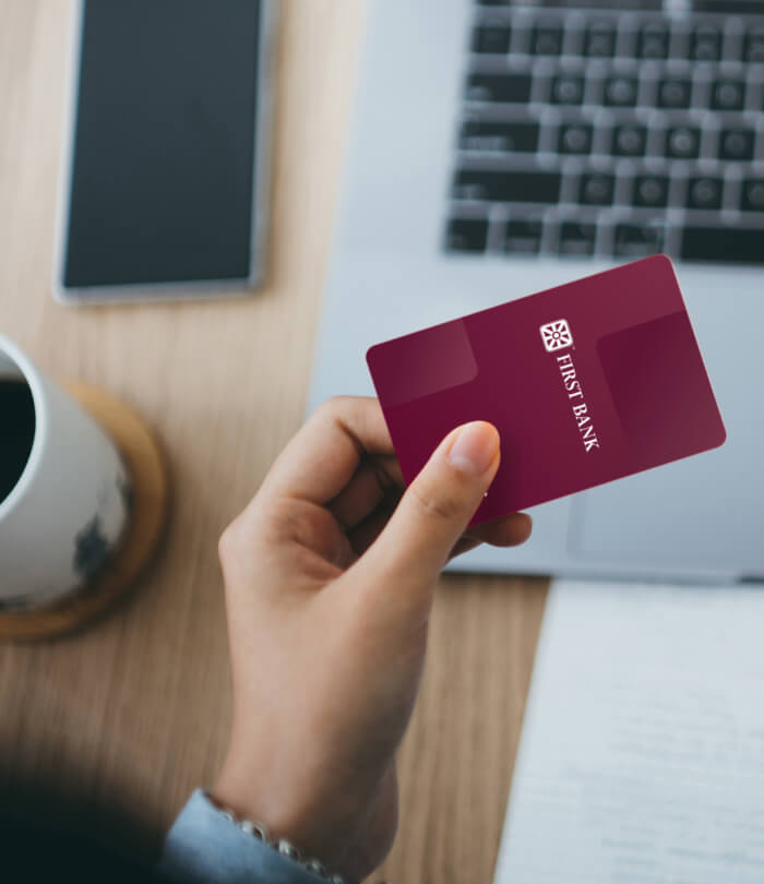 Personal debit card in hand at computer