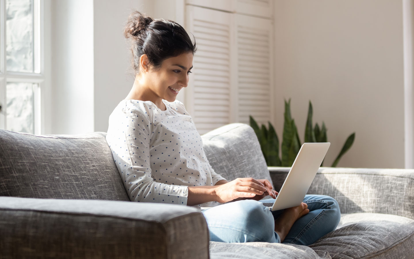 smiling woman on couch with laptop